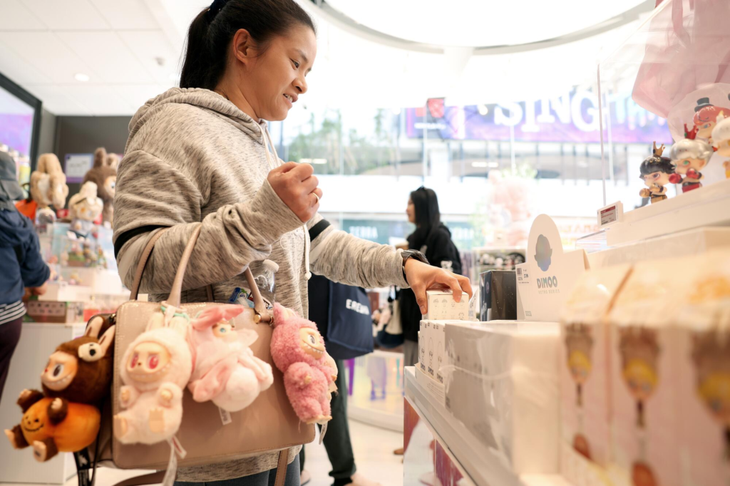 A collector browsing in-person display shelves inside a Pop Mart retail store.